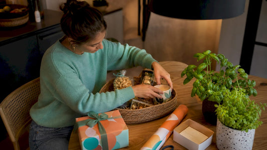 Een vrouw zit aan tafel en stelt een originele cadeauset samen.